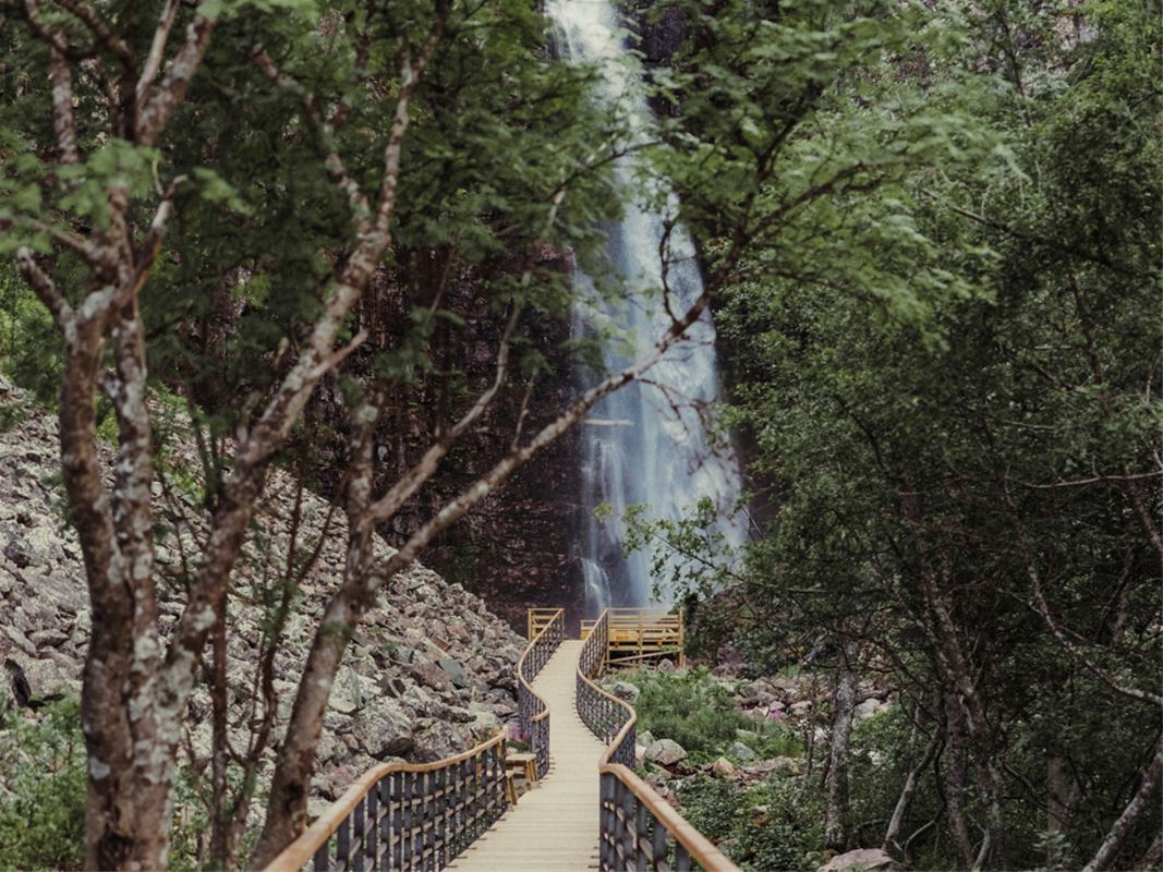 Gångbro mot ett högt vattenfall.