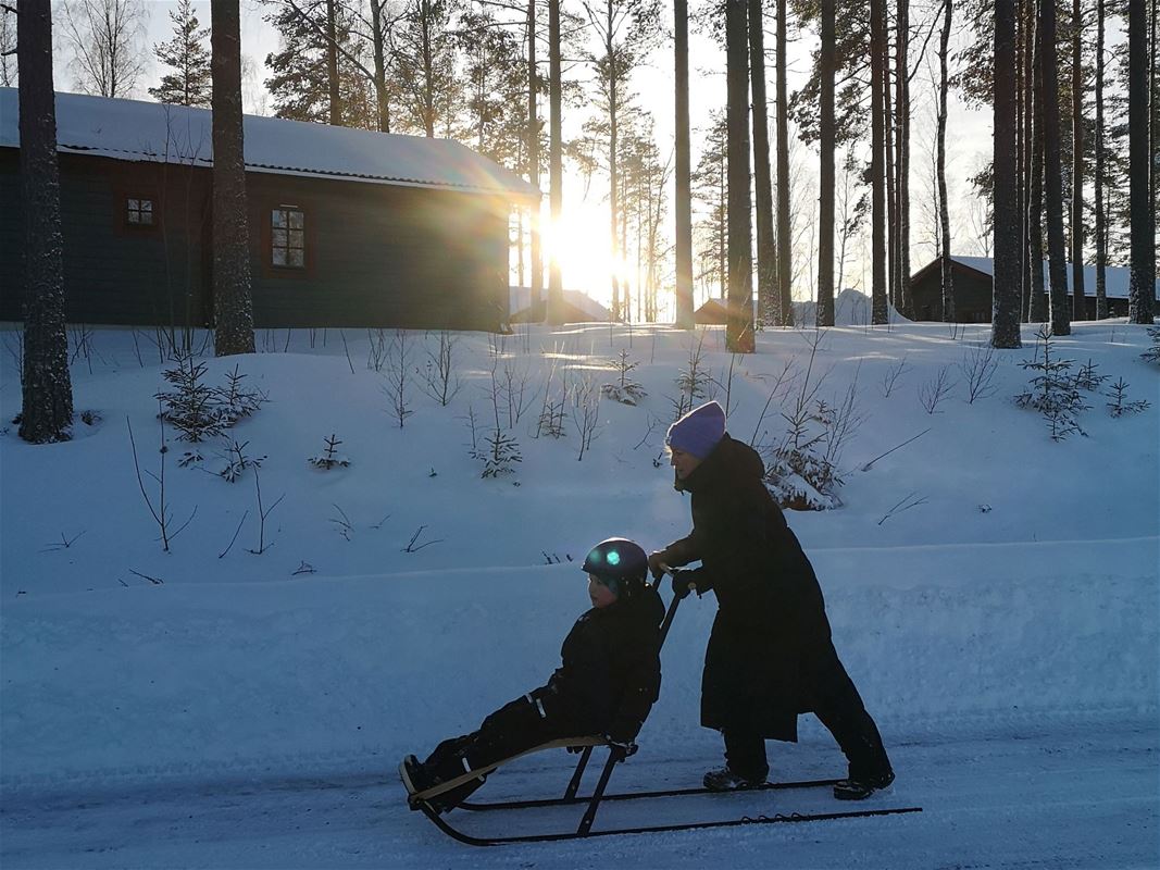 Kvinna kör sparl med barn vintertid.