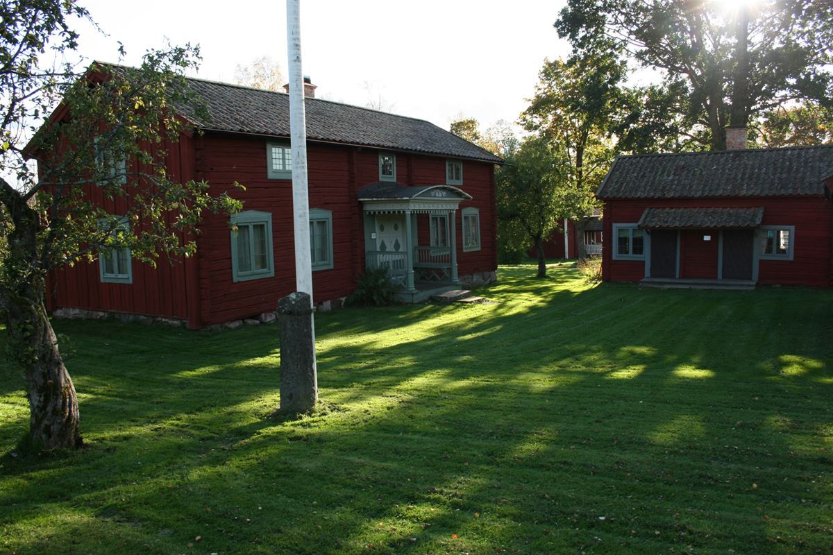 Lawn, two red timber buildings, one of them with two floors and one smaller.