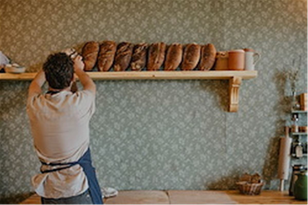 A person placing bread on a shelf.