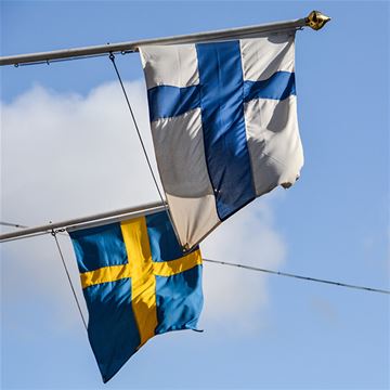 En svensk och en finsk flagg som vajar i vinden.