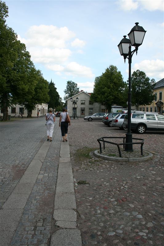 Two persons walking on cobbeld road.
