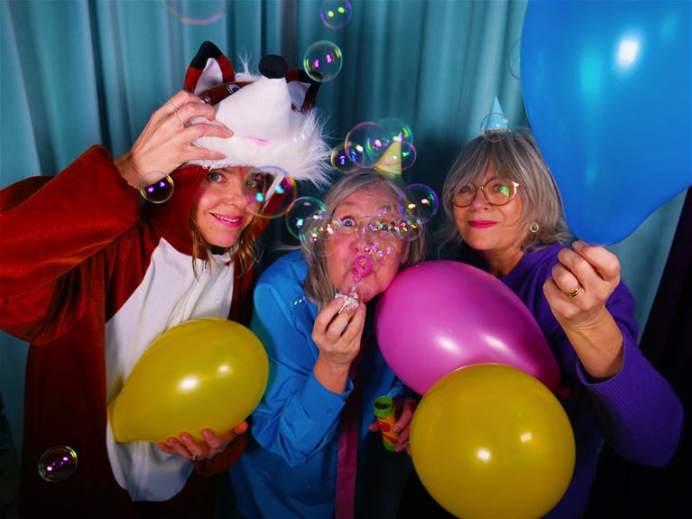 Ett foto med tre personer. en utklädd till räv och två med partyhattar. Ballonger och såpbubblor.