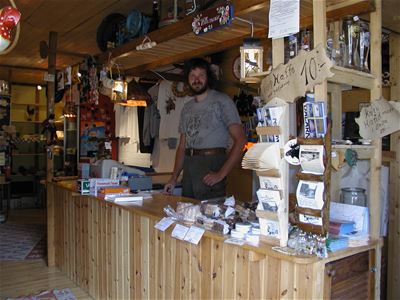 The host behind a wooden reception desk with postcards and souvenirs.