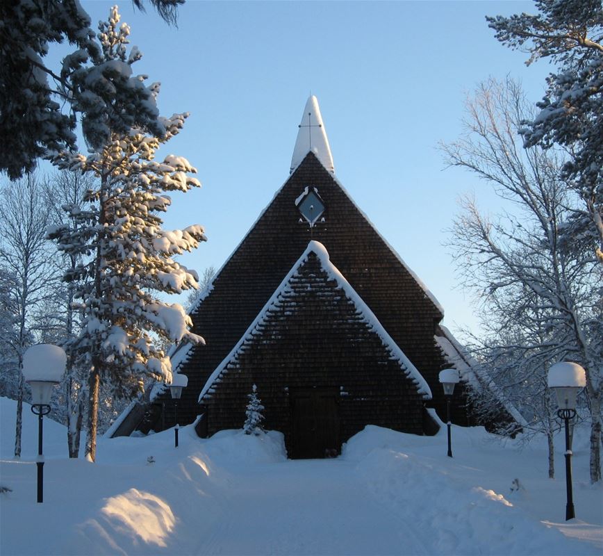 Vintrig bild av kapellet med snö längs kanten av vägen och lyktstolpar