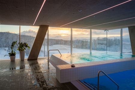 Indoor swimming pool with a view of snowy landscape and sunset