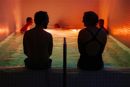 People relaxing in a small indoor pool with dim lighting