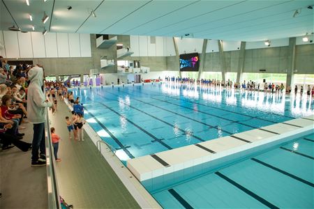 Indoor swimming pool with spectators and the sign TROMSØ BADET on the wall