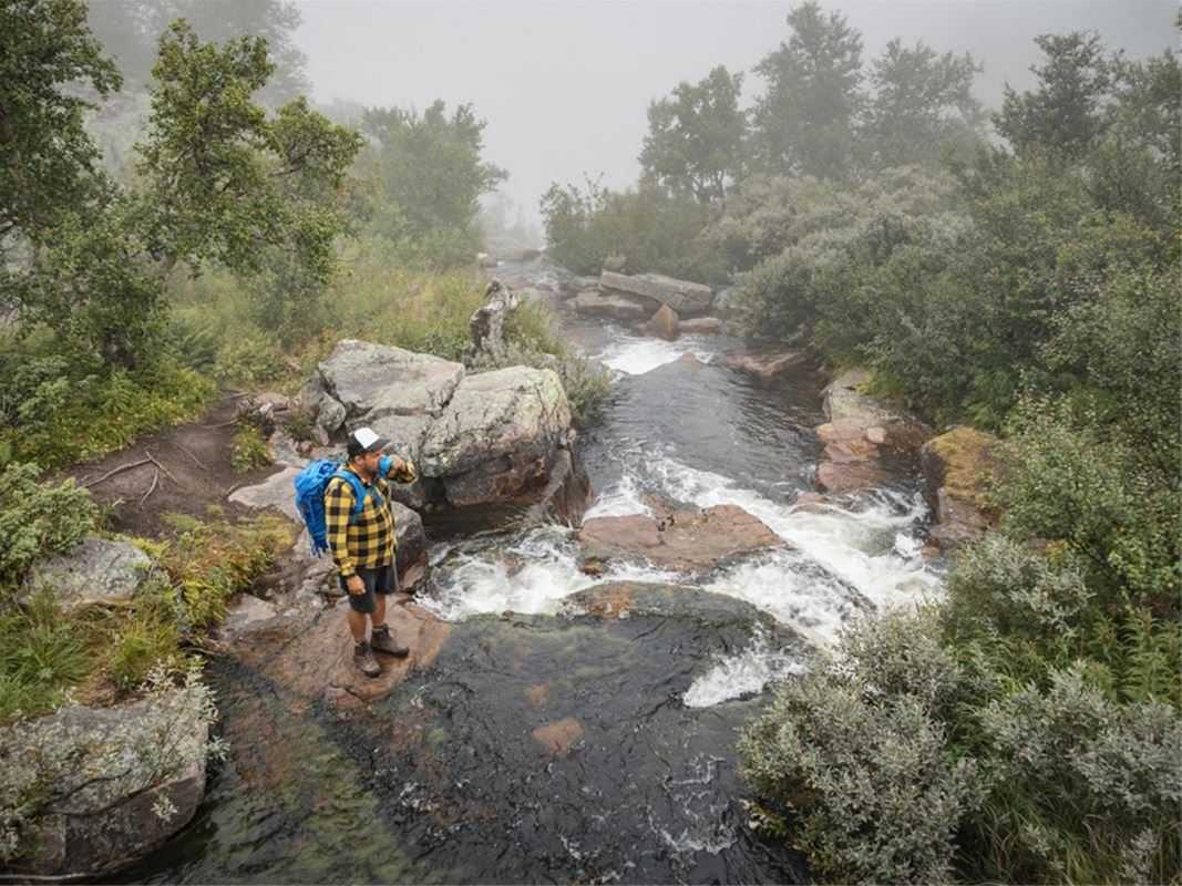 People with backpacks by a stream.