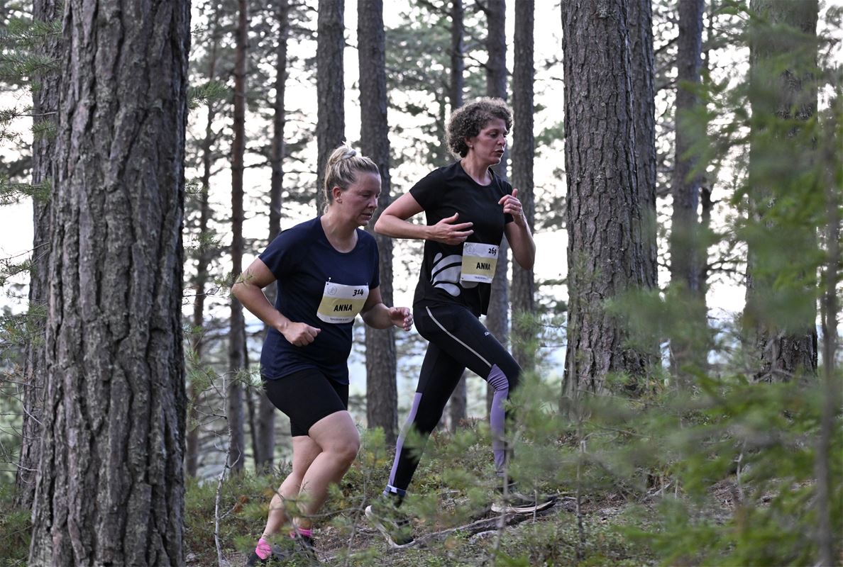 Två damer springer i skogen.