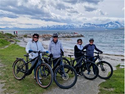 Four people with their bikes by the beach