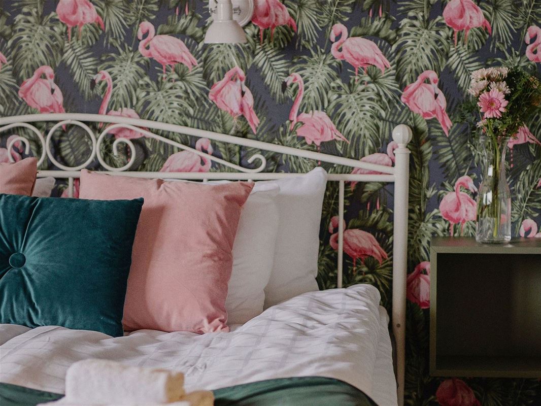 En säng med flamingotapeter.
