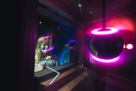 Person looking at an illuminated spherical object through a glass window.