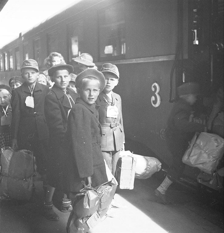 Finska krigsbarn står framför ett tåg med lappar runt halsen