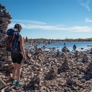 A person with a backpack standing next to a pile of rocks.