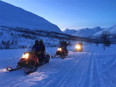 Snøskutere kjører blandt fjellene