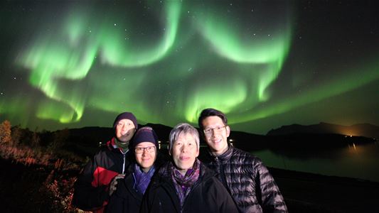 En gruppe gjester som tar et bilde under nordlyset