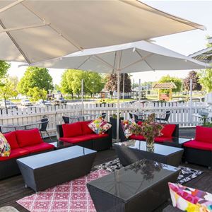 A patio with a white umbrella and red furniture.