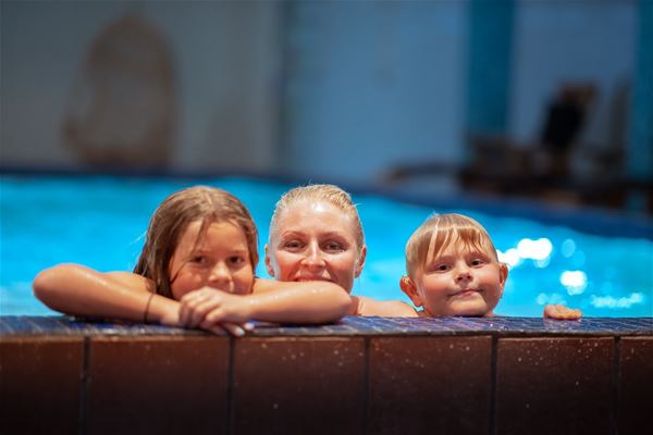A person and two children in a pool. 