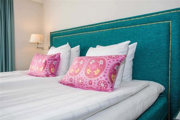 A bed with pink pillows and a blue headboard. 