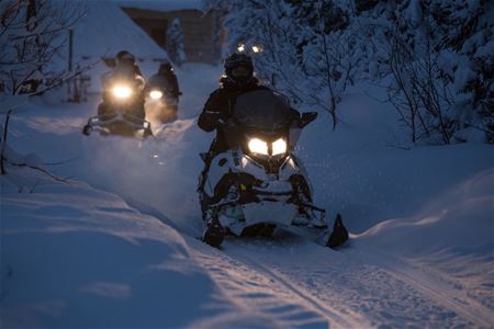 A snow scooter driving in the dark
