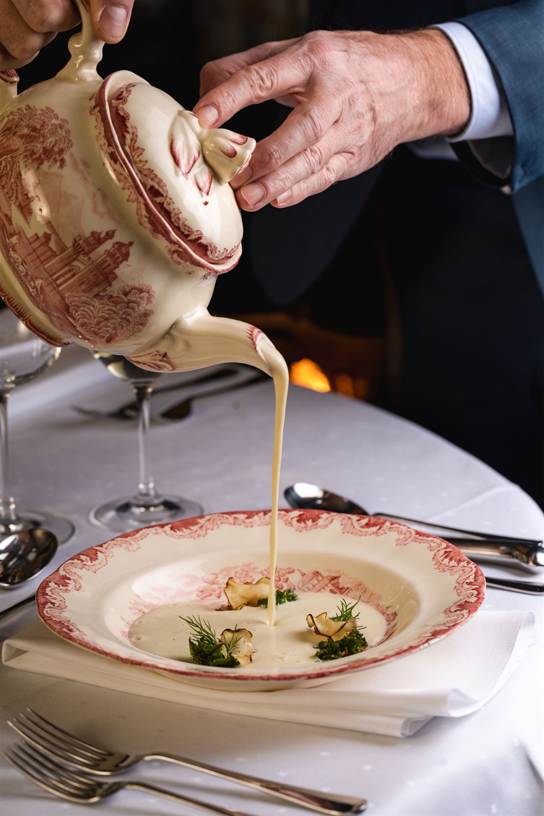 A person pouring soup into a plate.