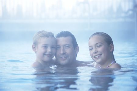 Dad with two children in the steam in the outdoor pool.