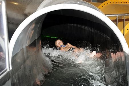 A child comes riding on his back out of the water slide tunnel.