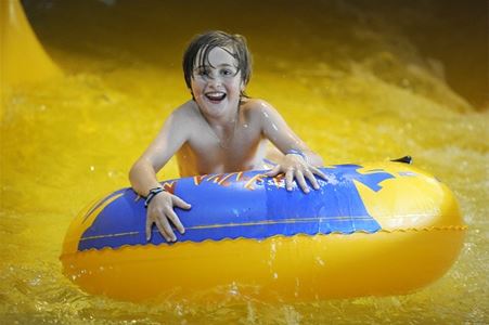 Boy riding a big bathing ring in the water slide.