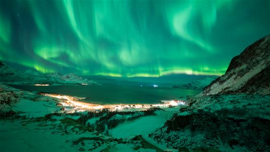 View of the northern lights with a small village in front
