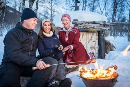 People grill sausages over the fire